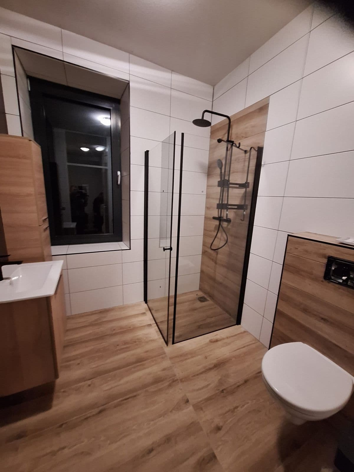 Badkamer met houtlook tegels en zwarte inloopdouche, gerenoveerd door Loodgieter Akif